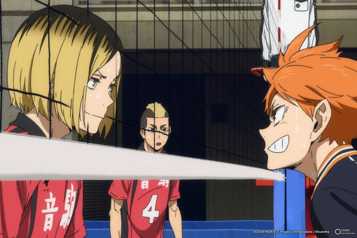 A blond boy in a red uniform and an orange-haired boy in a black uniform face off through a volleyball net in Haikyu!! The Dumpster Battle