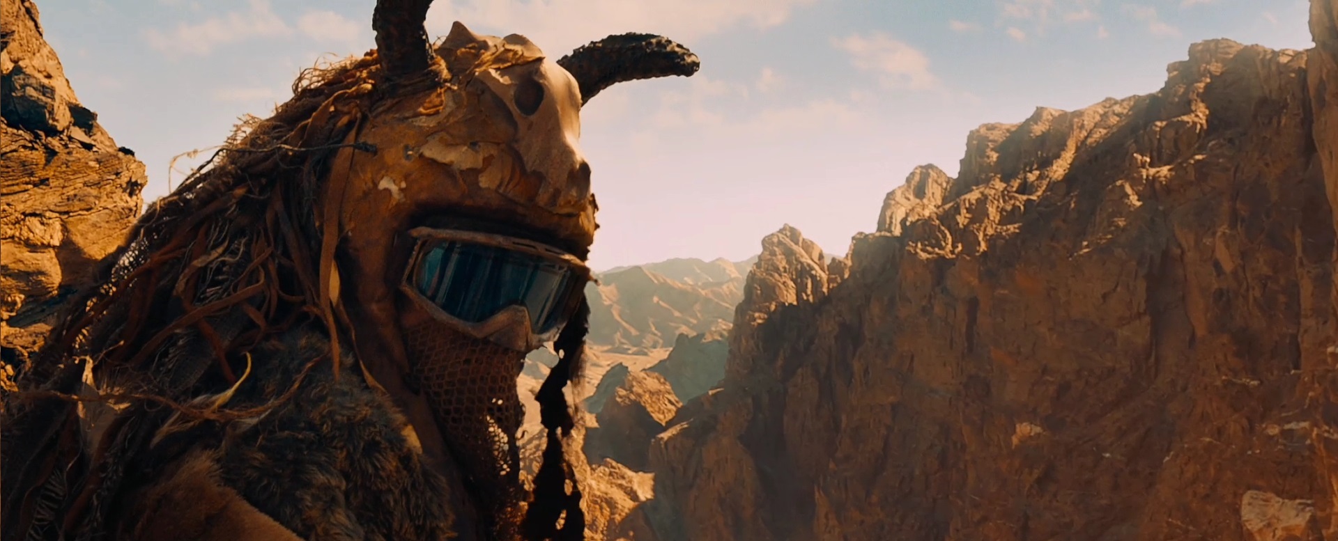 The leader of the Rock Riders looks towards the camera, with mountains in the background, in Mad Max: Fury Road